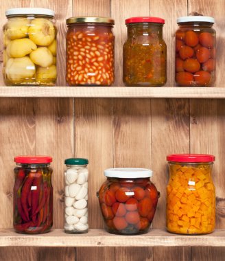 Preserved  vegetable on shelf near a brown wooden wall clipart