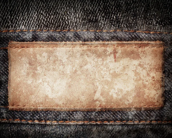 Grunge, étiquette de jeans en cuir teinté cousu sur jeans . — Photo