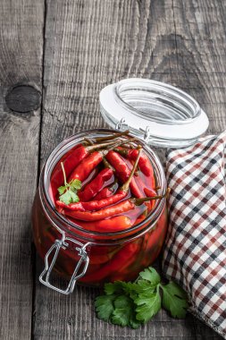 Kırsal masada ahşap kasede marine edilmiş kırmızı baharatlı biber. 