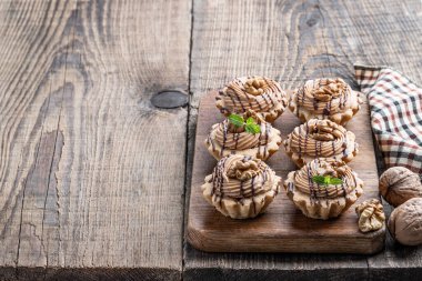 Krem şantili kısa hamurlu pasta ve ahşap masada ceviz. 