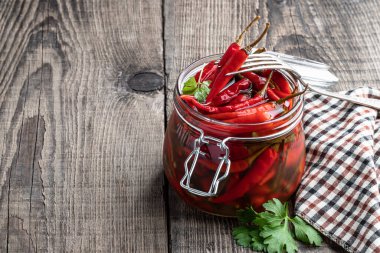 Kırsal masada ahşap kasede marine edilmiş kırmızı baharatlı biber. 