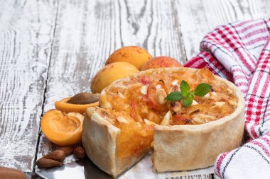 Beyaz ahşap masada bademli ev yapımı kayısı turtası. 