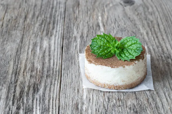 Ahşap kırsal masada naneli yapraklarla süslenmiş mini cheesecake. 