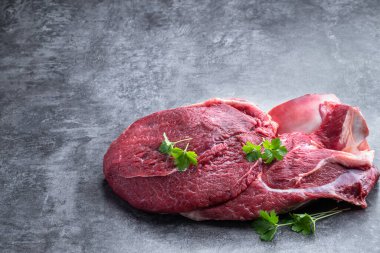 Gri taşlı arka planda kemik olan çiğ dana eti dilimi. 