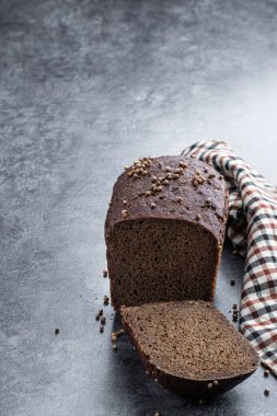 Gri taş arka planda kişniş tohumlu ev yapımı koyu çavdar ekmeği. 