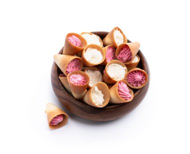 Kırbaçlanmış beyaz ve pembe kremalı mini külahlı kurabiyeler beyaza izole edilmiş. 