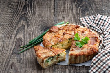 Savory  pie with bacon and green onion on wooden table 