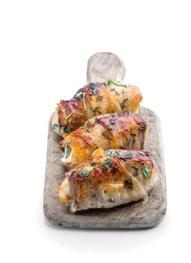 Chicken  breasts wrapped in bacon on wooden board isolated on white 