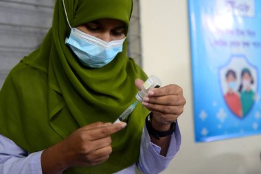Bangladeşli öğrenciler, 1 Kasım 2021 'de Bangladeş' in Motijheel bölgesindeki İdeal Okul ve Kolej Merkezi 'nde Pfizer COVID-19 aşısının ilk dozunu almayı beklerken kayıt kartlarıyla ayakta duruyorlar..