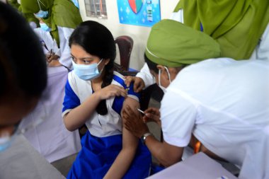 Bangladeşli öğrenciler, 1 Kasım 2021 'de Bangladeş' in Motijheel bölgesindeki İdeal Okul ve Kolej Merkezi 'nde Pfizer COVID-19 aşısının ilk dozunu almayı beklerken kayıt kartlarıyla ayakta duruyorlar..