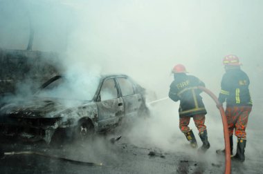 Dhaka 'daki yirmi parti ittifakı tarafından 6 Ocak 2015' te uygulanan ülke çapındaki abluka programının ilk gününde muhalefet göstericileri tarafından ateşe verilen yanan araçları itfaiyeciler söndürüyor..