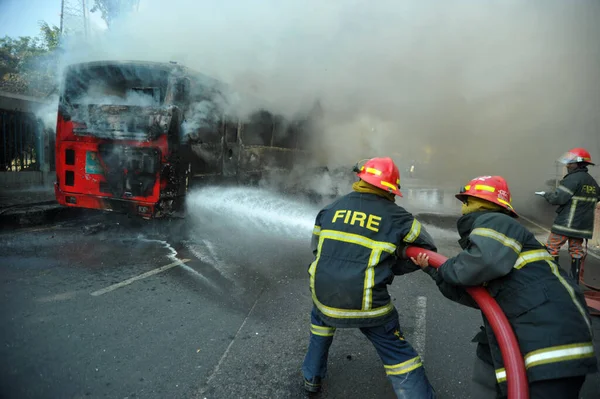 Dhaka 'daki yirmi parti ittifakı tarafından 6 Ocak 2015' te uygulanan ülke çapındaki abluka programının ilk gününde muhalefet göstericileri tarafından ateşe verilen yanan araçları itfaiyeciler söndürüyor..
