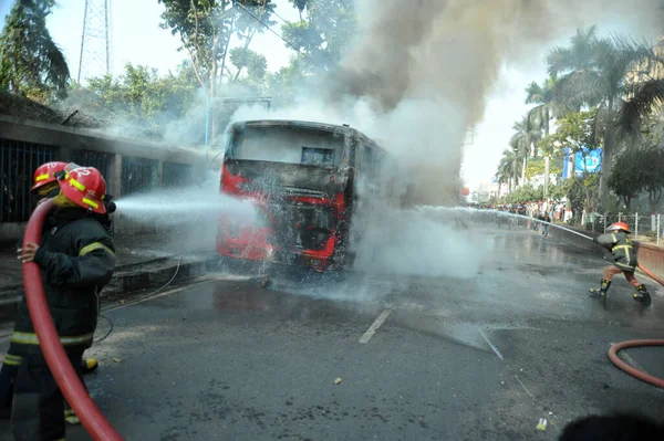 Dhaka 'daki yirmi parti ittifakı tarafından 6 Ocak 2015' te uygulanan ülke çapındaki abluka programının ilk gününde muhalefet göstericileri tarafından ateşe verilen yanan araçları itfaiyeciler söndürüyor..