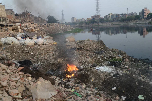 İnsanlar 19 Mart 2022 'de Bangladeş' in Dhaka kentindeki Buriganga Nehri kıyısında çöp yakarak zehirli duman yaratıyor. Dhaka, inşaat, araç emisyonları ve tuğla fırınlarının atıklarıyla dünyanın en kirli şehirlerinden biri olarak sıralamaya devam ediyor.