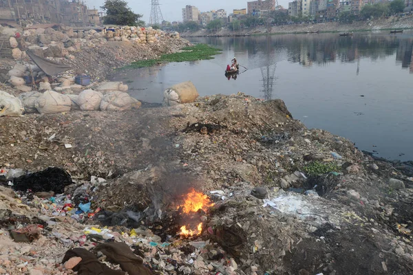 İnsanlar 19 Mart 2022 'de Bangladeş' in Dhaka kentindeki Buriganga Nehri kıyısında çöp yakarak zehirli duman yaratıyor. Dhaka, inşaat, araç emisyonları ve tuğla fırınlarının atıklarıyla dünyanın en kirli şehirlerinden biri olarak sıralamaya devam ediyor.