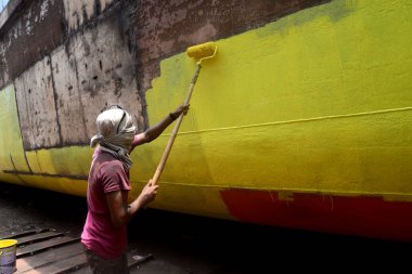 Liman işçileri 22 Temmuz 2022 'de Bangladeş' in Dhaka kentindeki Buriganga Nehri kıyısındaki bir geminin gövdesindeki bakım çalışmalarına devam ediyorlar.