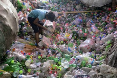 Çocuk işçiler, 27 Temmuz 2022 'de Bangladeş' in Dhaka kentindeki bir geri dönüşüm fabrikasında polietilen tereftalat (PET) şişelerini sınıflandırıyorlar. Plastik şişelerin geri dönüşümü son birkaç yılda büyüyen bir iş haline geldi.