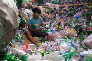 Child laborers sort through polyethylene terephthalate (PET) bottles in a recycling factory in Dhaka, Bangladesh, on July 27, 2022. Recycling plastic bottles has become a growing business over the last couple of years as well as helping to protect th