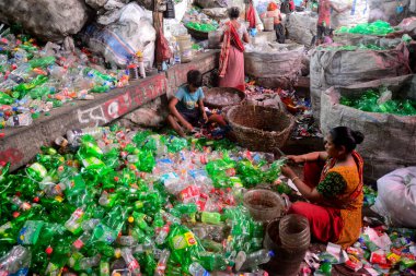 İşçiler, 27 Temmuz 2022 'de Bangladeş' in Dhaka kentindeki bir geri dönüşüm fabrikasında polietilen tereftalat (PET) şişelerini sınıflandırıyorlar. Plastik şişelerin geri dönüşümü son birkaç yıl içinde büyüyen bir iş haline geldi.