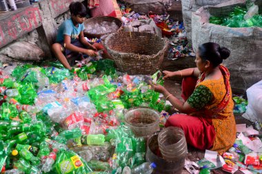 Kadın işçiler, 27 Temmuz 2022 'de Bangladeş' in Dhaka kentindeki bir geri dönüşüm fabrikasında polietilen tereftalat (PET) şişelerini sınıflandırıyorlar. Plastik şişelerin geri dönüşümü son birkaç yılda büyüyen bir iş haline geldi.