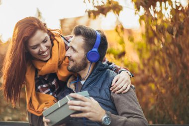 Parkta hediyeleri olan genç bir çift. Adam karısına hediye kutusu veriyor..