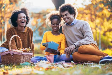 Karışık aile parkta piknik yaparken eğleniyor ve açık bir hediye..