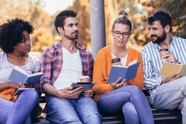 Üniversite derslerinden sonra öğrenciler parkta bankta oturup konuşuyorlar..