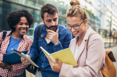 Üniversite öğrencileri kampüste açık havada okuyor.