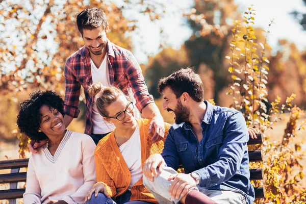 Group of young people having fun outdoors on park bench