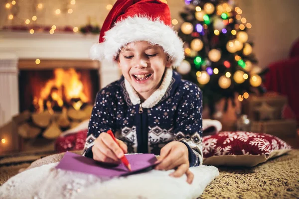 Мальчик Пишет Письмо Санта Клаусу Красной Шляпе Возле Елки — стоковое фото