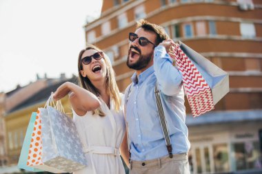 Bir çift turist şehir caddesinde yürüyor, alışveriş yapıyor, eğleniyorlar.