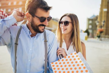 Bir çift turist şehir caddesinde yürüyor, alışveriş yapıyor, eğleniyorlar.