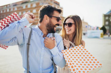 Bir çift turist şehir caddesinde yürüyor, alışveriş yapıyor, eğleniyorlar.