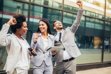 İş ekibi zaferi kutluyor, dijital tablete bakıyor..