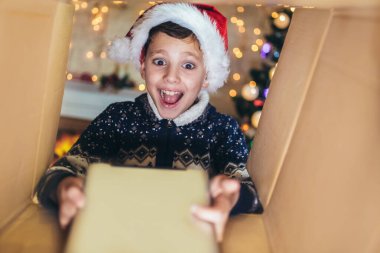 Noel hediyesini açan süpriz çocuk. Küçük çocuk ağaç ve şöminenin yanında eğleniyor..
