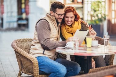 Kafede dijital tablet ve kredi kartı kullanan genç bir çift..