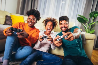 Afrika kökenli Amerikalı bir aile birlikte video oyunu oynuyor ve evde eğleniyor.