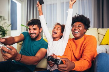 Afrika kökenli Amerikalı bir aile birlikte video oyunu oynuyor ve evde eğleniyor.