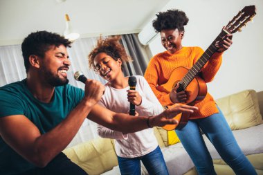 Ailesiyle birlikte karaoke mikrofonunda en sevdiği şarkıyı söyleyen bir kız.