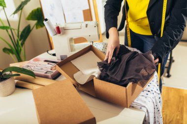 Terzi kadın evde. İnternetten yeni siparişleri kabul ediyorlar ve müşteriler için mal paketliyorlar..