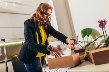 Terzi kadın evde. İnternetten yeni siparişleri kabul ediyorlar ve müşteriler için mal paketliyorlar..