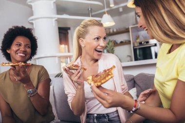 Evdeki kanepede şarap ve pizzayla mutlu genç bayan arkadaşlar.. 