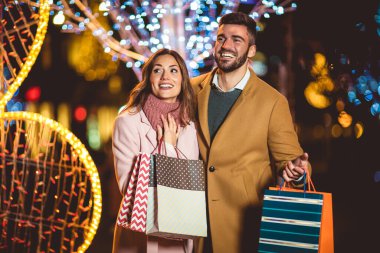 Genç romantik çift ellerinde alışveriş torbalarıyla Noel 'den önce dışarıda eğleniyorlar..