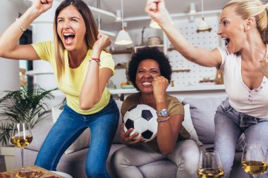 Bir grup neşeli bayan arkadaş futbol maçı izleyip zaferi evde kutluyorlar..