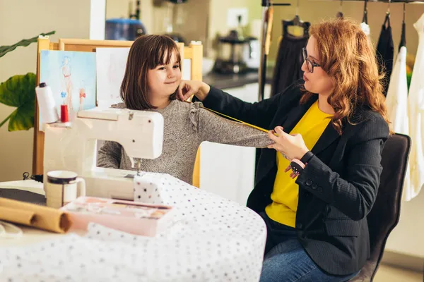 快乐的年轻女人和她的女儿一起缝纫 她在家里工作 — 图库照片