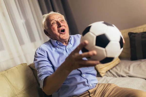 Starší Muž Sedí Pohovce Dívá Televizi Emocionálně Křičí Drží Fotbalový — Stock fotografie