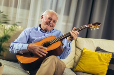 Son sınıf öğrencisi evde gitar çalıyor.
