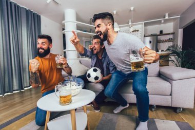 Çok heyecanlı arkadaşlar evde, içeride futbol maçı izleyerek eğleniyorlar. Arkadaşlık, eğlence, spor, dinlenme, ev partisi konsepti