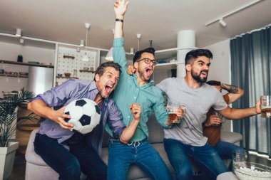 Çok heyecanlı arkadaşlar evde, içeride futbol maçı izleyerek eğleniyorlar. Arkadaşlık, eğlence, spor, dinlenme, ev partisi konsepti