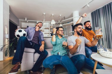 Çok heyecanlı arkadaşlar evde, içeride futbol maçı izleyerek eğleniyorlar. Arkadaşlık, eğlence, spor, dinlenme, ev partisi konsepti